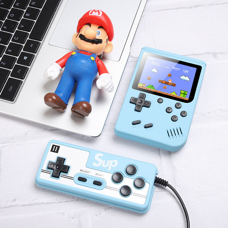 Handheld game console with blue controller and Mario figurine on a white surface