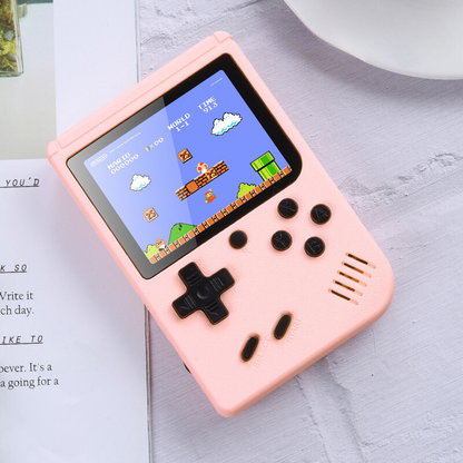 Pink handheld gaming console with a classic game displayed on the screen, placed on a surface.