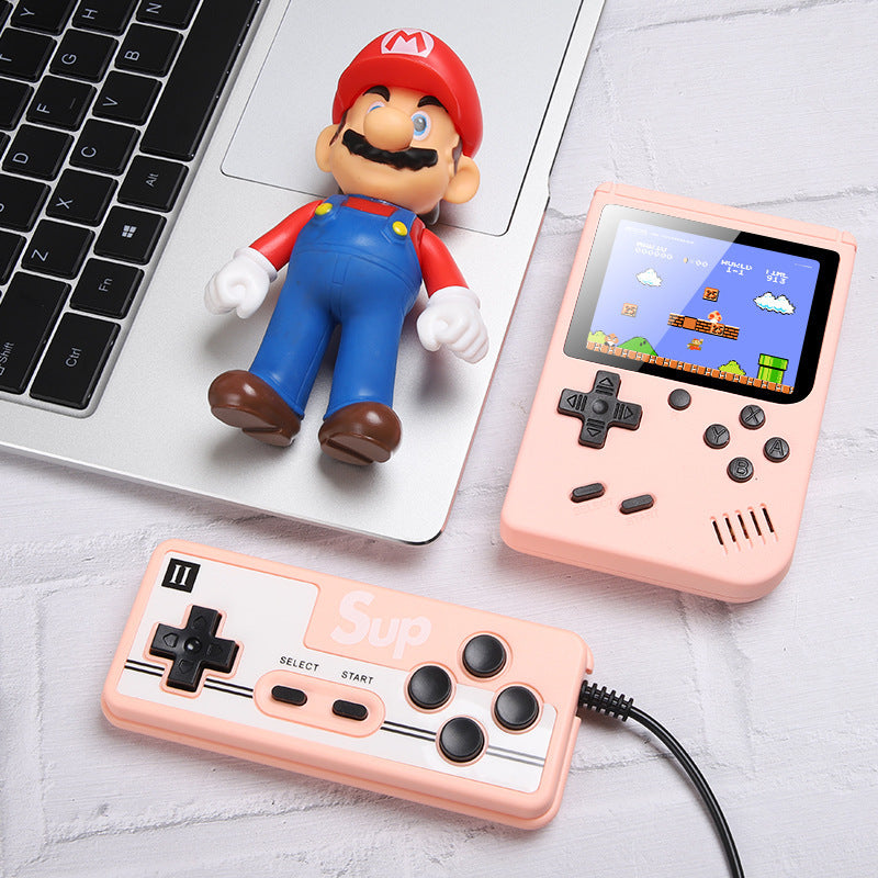 Handheld gaming console with controller and Mario figurine on a light surface